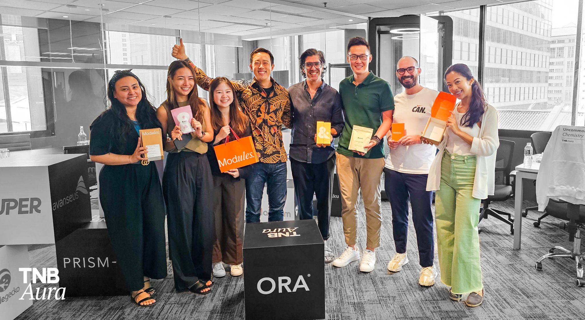 The TNB Aura team standing together holding materials from their new portfolio company ORA